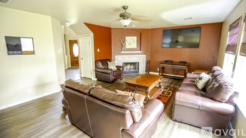 A living room with a brown leather couch and a fireplace.