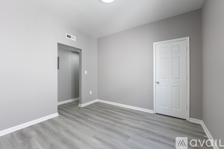 A room with a white door and a grey wall.