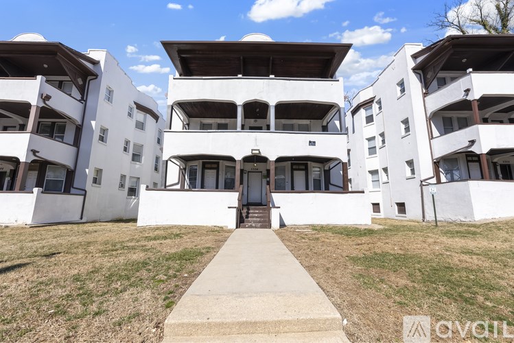 A white building with a brown roof and a walkway leading to the entrance.