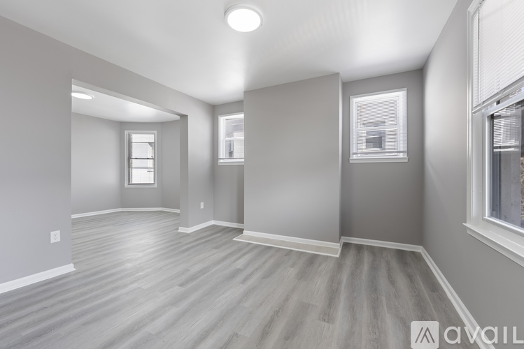 A spacious room with wooden flooring and white walls.