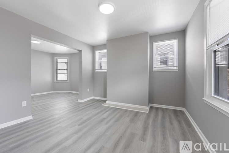 A spacious room with wooden flooring and white walls.