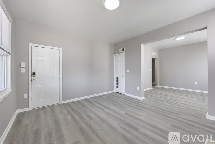 A spacious room with light grey walls and a wooden floor.