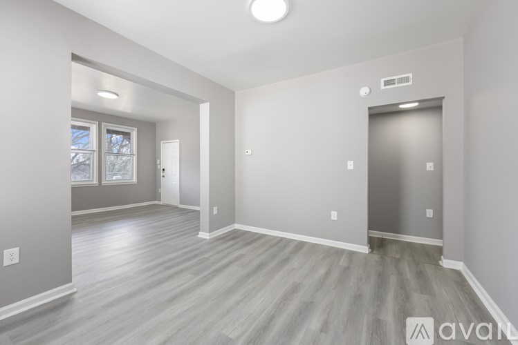 A spacious room with wooden flooring and a closed door on the right.
