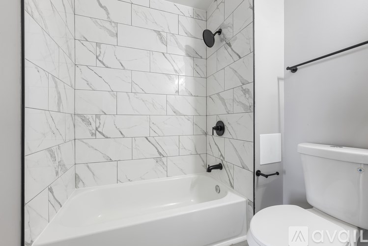 A white bathroom with a marble tile wall and a white bathtub.