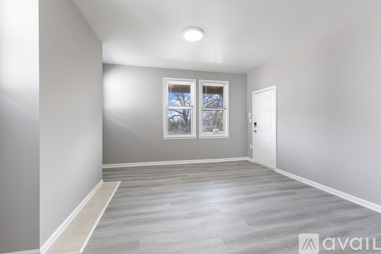 A spacious room with grey walls and a large window with a view of trees outside.