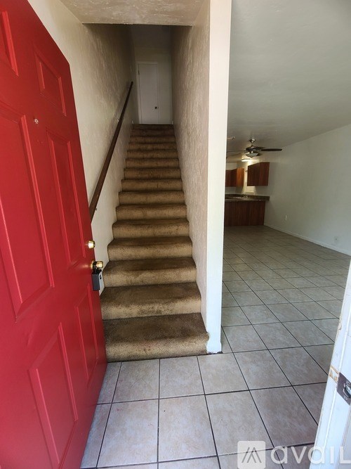 A red door is on the left of a staircase.
