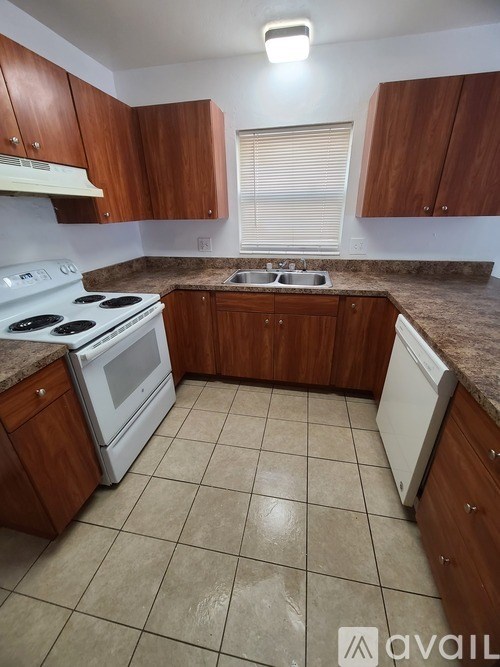 A kitchen with a white stove and brown cabinets.