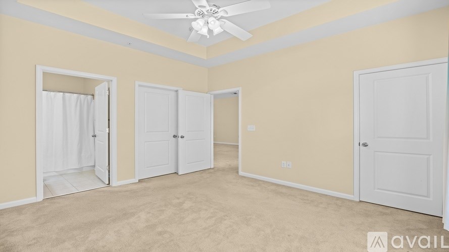 A room with a ceiling fan and three doors.