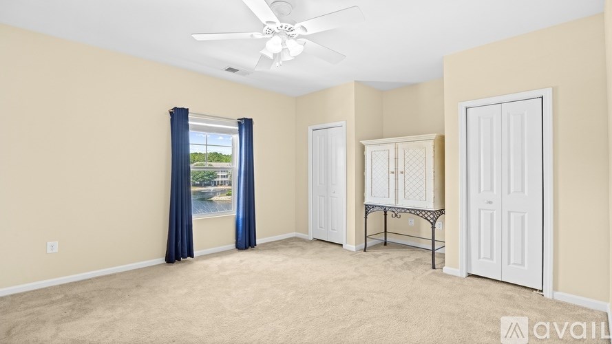 A room with a ceiling fan and a window with blue curtains.