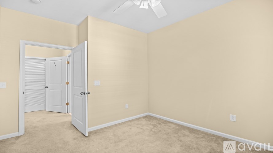 A room with a carpeted floor and a ceiling fan.