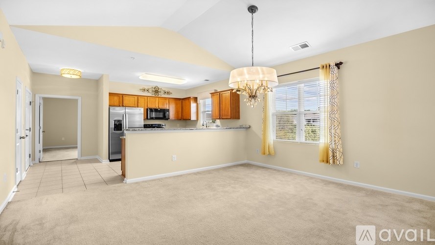 A spacious living room with a kitchen area in the background.