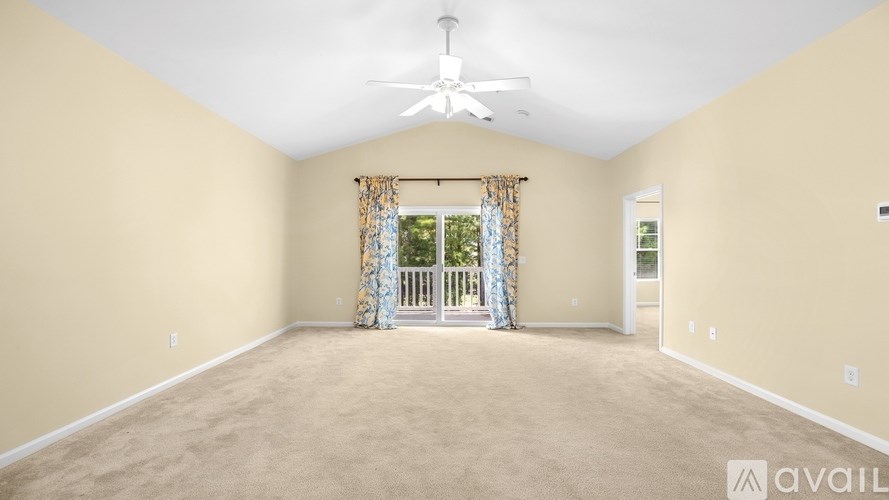 A spacious room with a ceiling fan and carpeted floor.