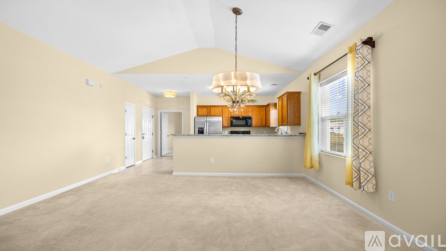 A spacious living room with a kitchen in the background.