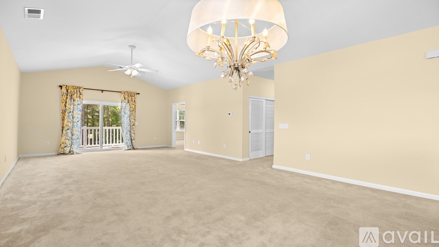 A spacious room with a chandelier and a fan.