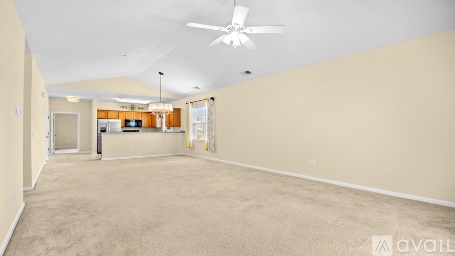 A spacious room with a ceiling fan and carpeted floor.