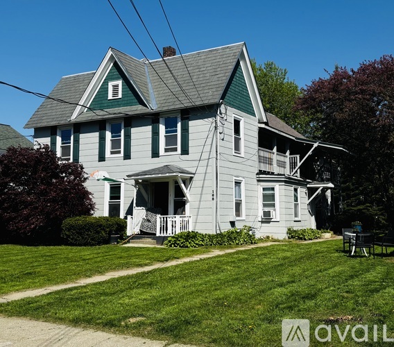A house with a green roof and white walls with a porch.