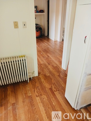 A white refrigerator is in a room with wooden floors.