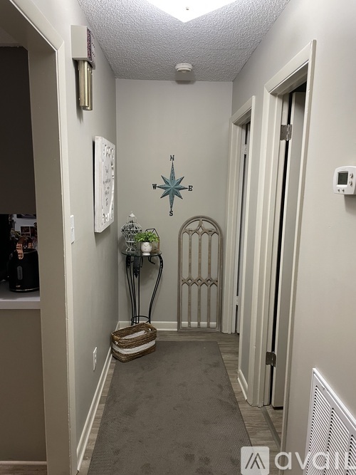A hallway with a carpeted floor, a door with a gate, and a wall with a compass hanging on it.