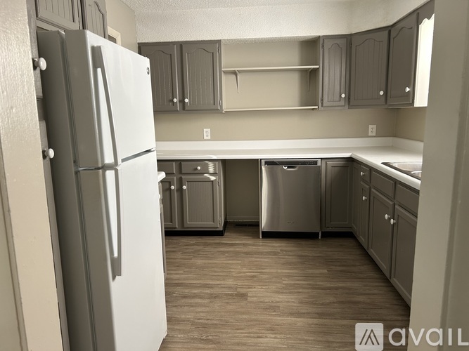 A kitchen with a white refrigerator and wooden floors.