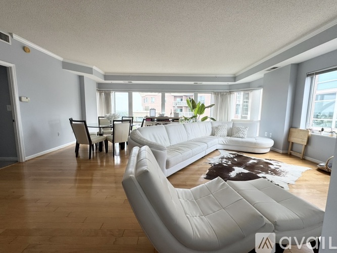 A living room with white furniture and a cowhide rug.