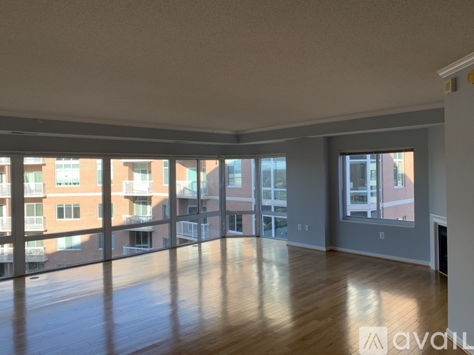 A spacious room with wooden floors and large windows overlooking a cityscape.