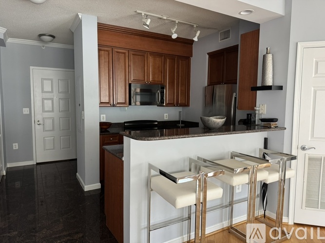 A kitchen with a white counter and bar stools.