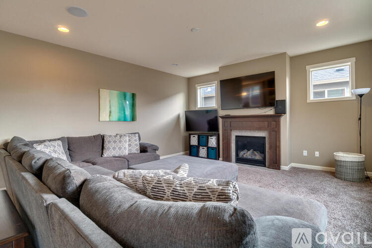 A living room with a grey couch and a fireplace.