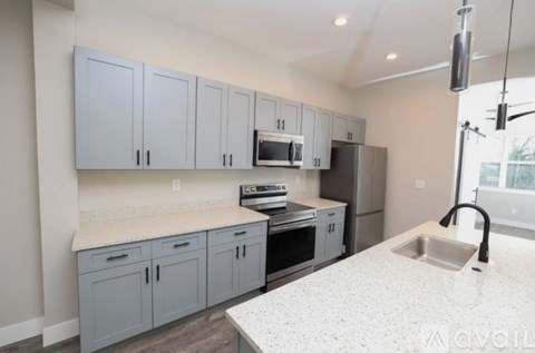 A kitchen with grey cabinets and a white countertop.