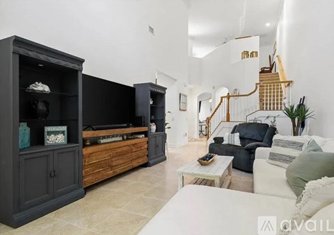 A living room with a white couch and a wooden staircase.