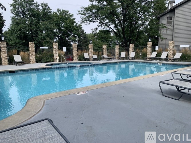 A pool surrounded by stone pillars and lounge chairs.