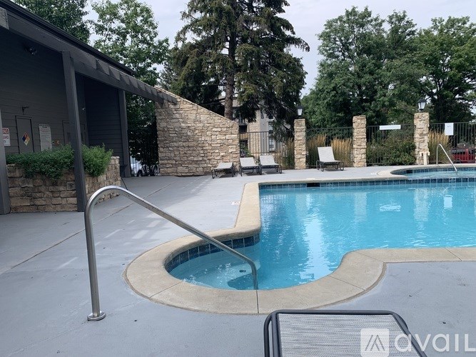 A pool with a stone wall and a metal railing.