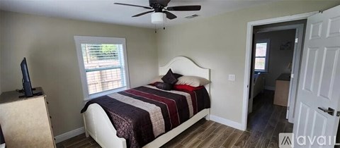 A bedroom with a bed, a ceiling fan, and a window.