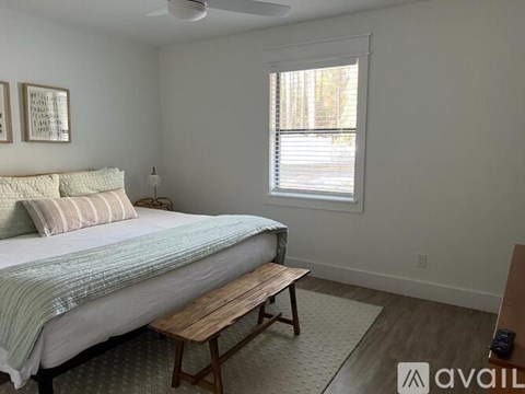 A bedroom with a bed, a bench, and a window.