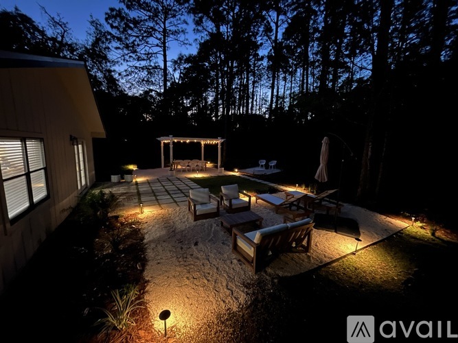 A backyard with a patio and a gazebo is lit up at night.
