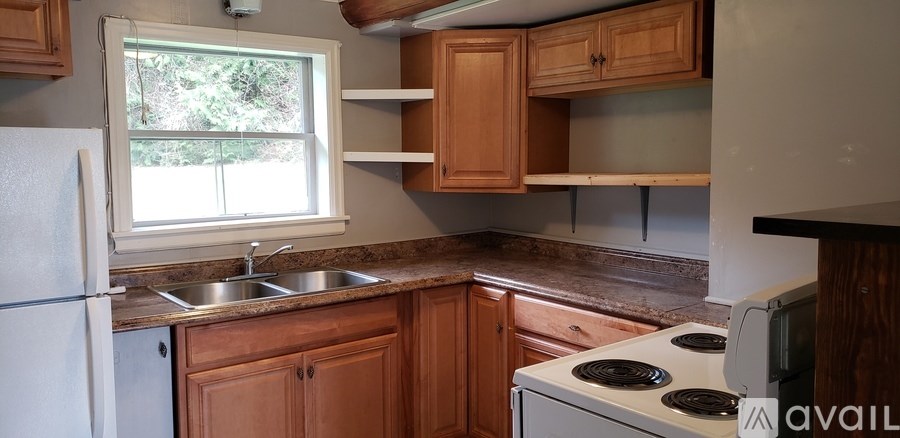 A kitchen with wooden cabinets and a white stove top oven.
