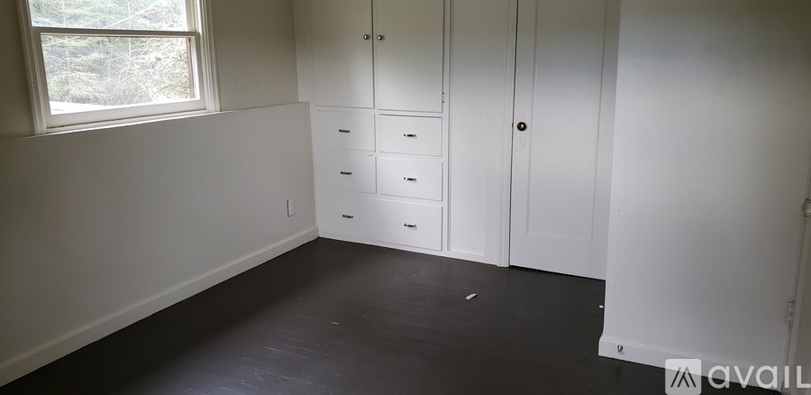A room with a window and a white cabinet with drawers.