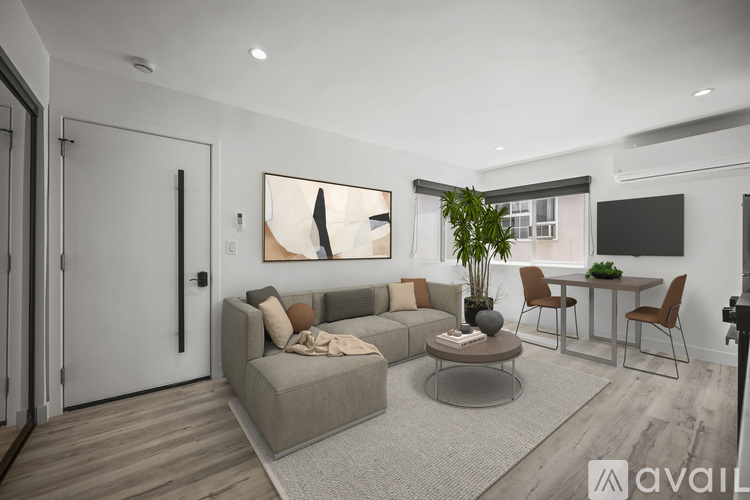 A living room with a grey sofa, a coffee table, and a dining table with chairs.