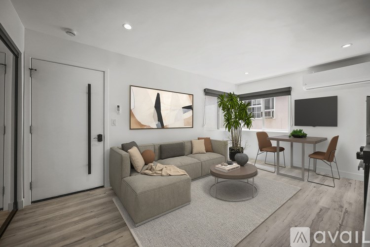 A living room with a grey sofa, a coffee table, and a dining table with chairs.
