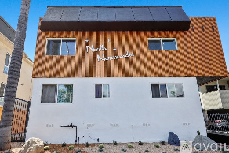 A building with a brown wooden facade and a white wall below the windows has a sign that says "North + Nandomie".