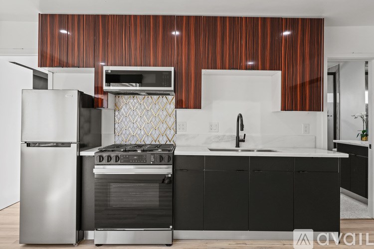 A modern kitchen with a stainless steel refrigerator and a black and white countertop.