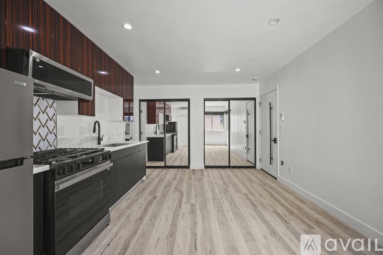 A modern kitchen with a stove top oven and a wooden floor.