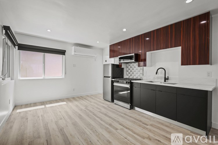 A modern kitchen with wooden floors and black cabinets.