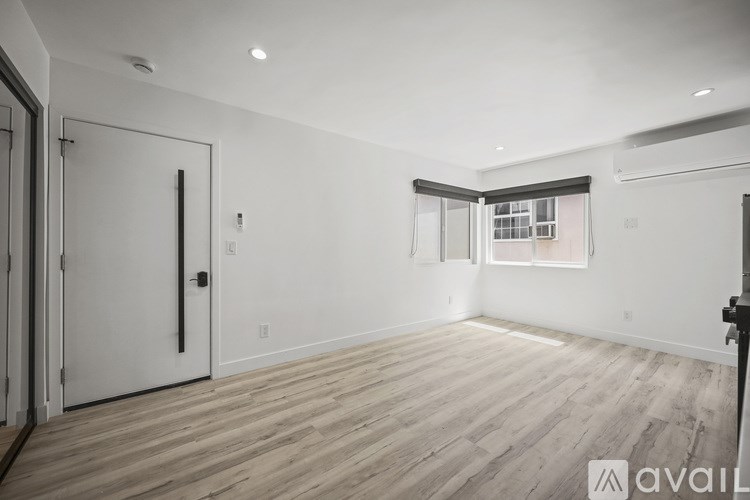 A spacious room with wooden flooring and a large window.