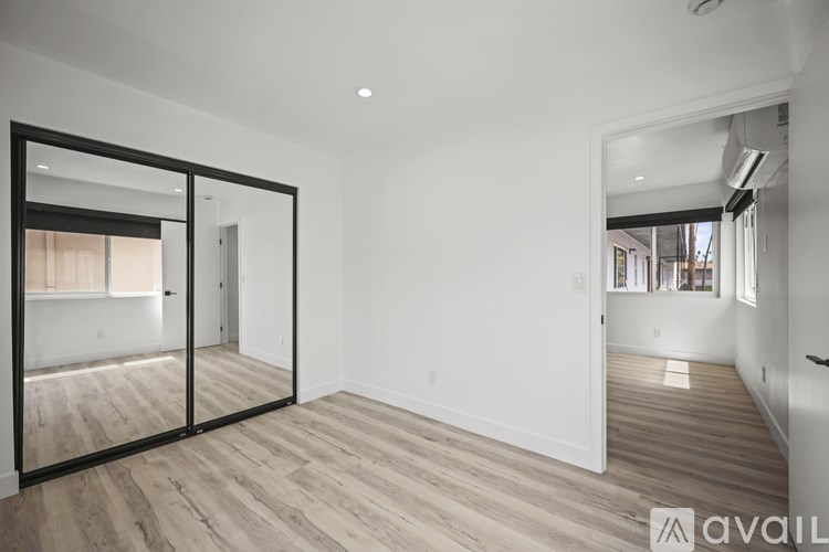 A spacious room with wooden flooring and a large mirror on the wall.