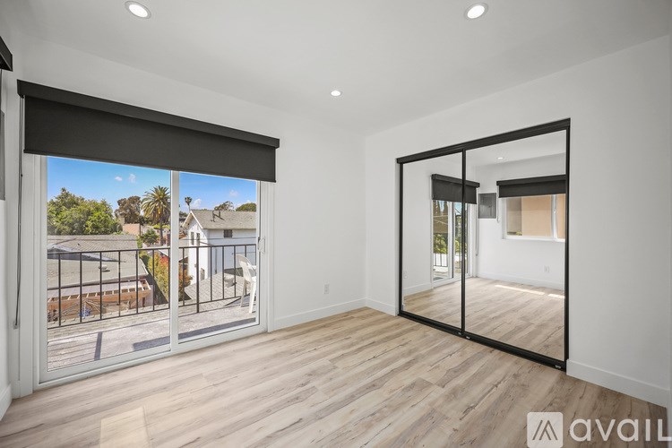 A spacious room with wooden flooring and a large mirror on the wall.