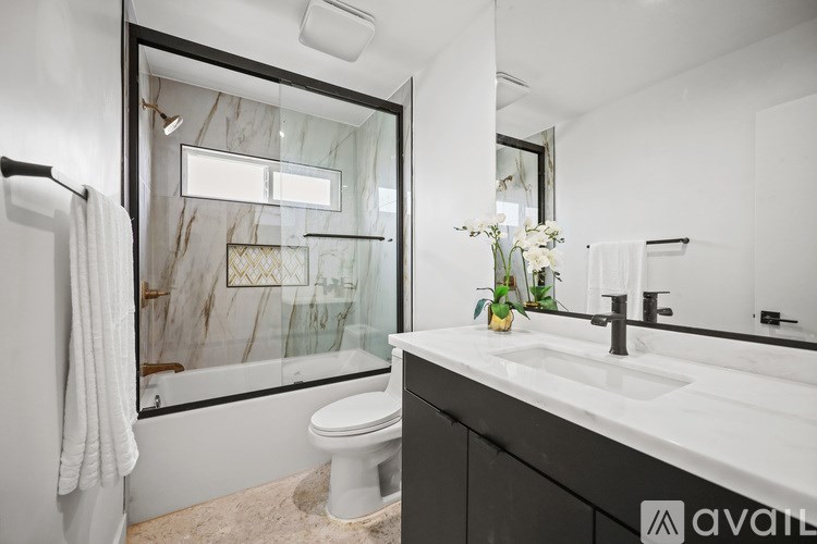 A bathroom with a marble patterned tub and a white toilet.