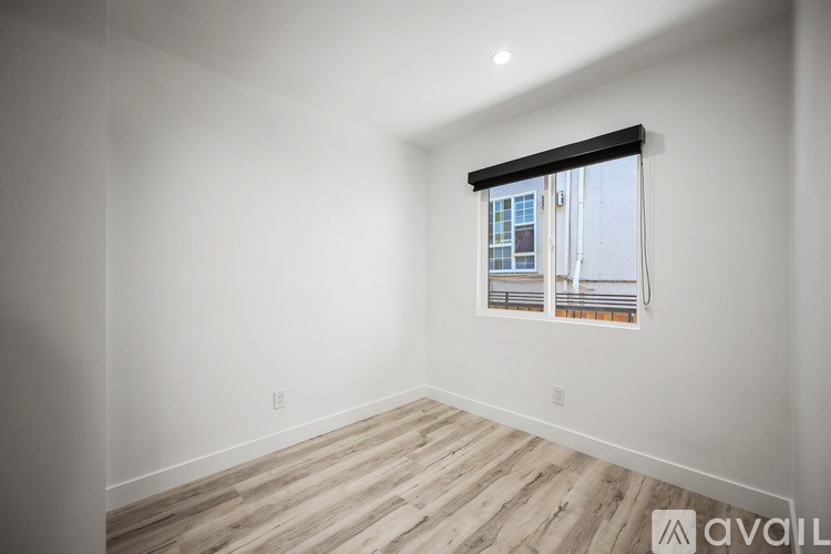 A room with wooden flooring and a window showing a cityscape outside.