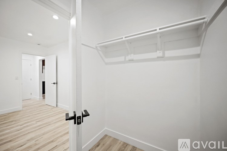 A white door with a black handle is in the middle of a hallway.