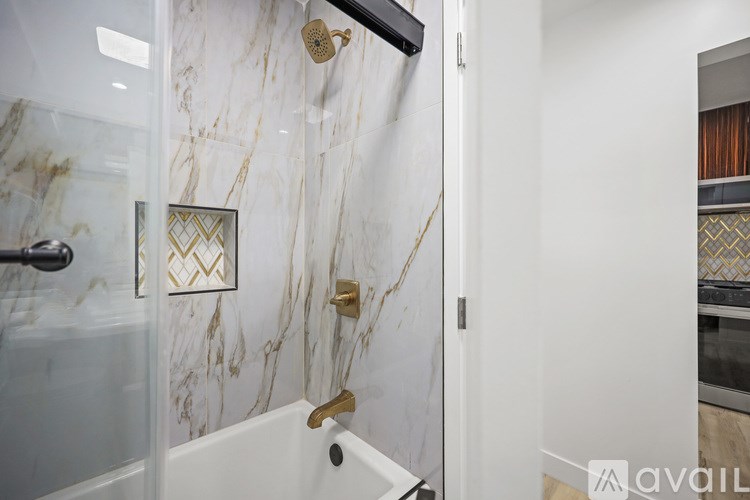 A bathroom with a marble wall and a glass shower door.
