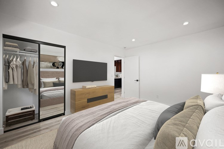 A bedroom with a large bed and a TV on the wall.